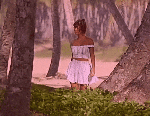 a woman in a crop top and skirt is standing in a forest