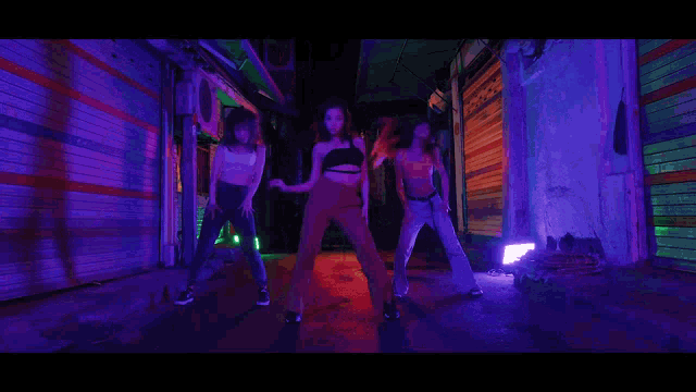 three women dancing in a dark alleyway with purple lights