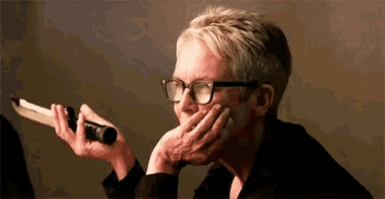 a woman wearing glasses is holding a microphone in her hand and talking into it .