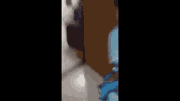 a man in a blue shirt and blue shorts is walking in a room .