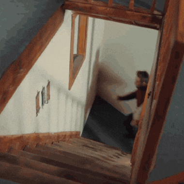 a person is walking down a set of wooden stairs in a house