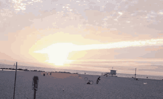 a sunset on a beach with a lifeguard tower in the background