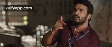 a man wearing headphones is pointing at something while sitting down .