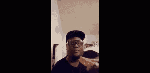 a man wearing sunglasses and a hat is eating a piece of pizza