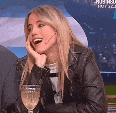 a woman in a leather jacket is holding a glass of wine and smiling