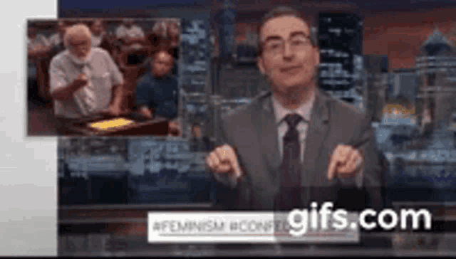 a man in a suit and tie is standing in front of a screen that says gifs.com on it
