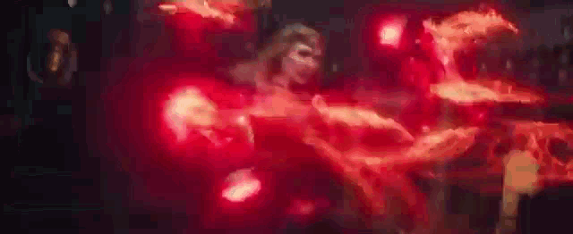 a woman in a red dress is surrounded by red flames in a dark room .
