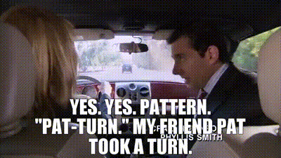a man in a suit and tie is driving a car and talking to a woman .