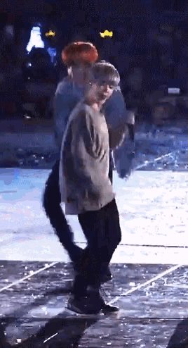 a couple of men are dancing on a stage with a crowd in the background