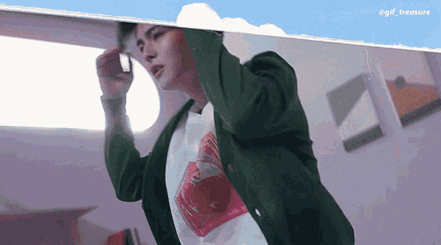 a man in a green jacket is standing in front of a mirror with the words gif treasure above him