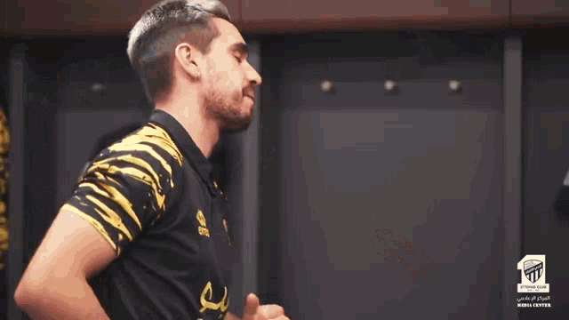 a man adjusts another man 's ear while wearing a shirt with the number 20 on it