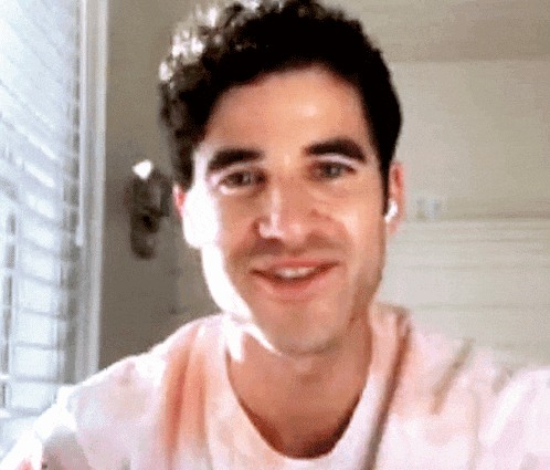 a close up of a man 's face smiling while wearing a pink shirt .