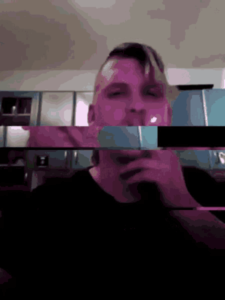 a man in a black shirt is smoking a cigarette in front of a kitchen