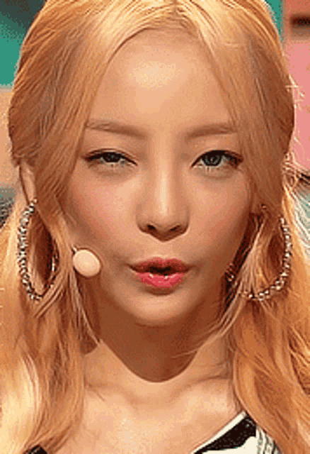 a close up of a woman 's face with blonde hair and hoop earrings