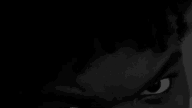 a black and white photo of a person 's eye in the dark .