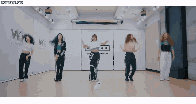 a group of women are dancing in a room with a sign that says amber