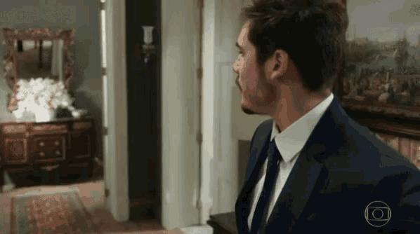 a man in a suit and tie is standing in front of a painting