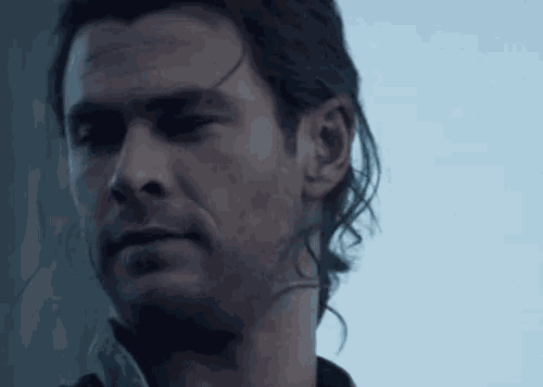 a close up of a man 's face with a beard and long hair .