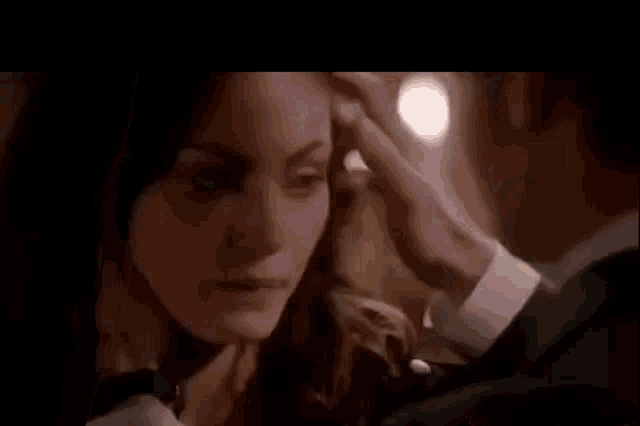 a man in a suit is touching a woman 's face in a close up .