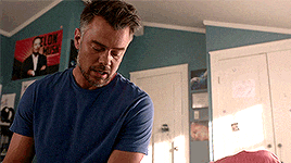 a man in a blue shirt is standing in a room with a poster on the wall that says ' lon musk '