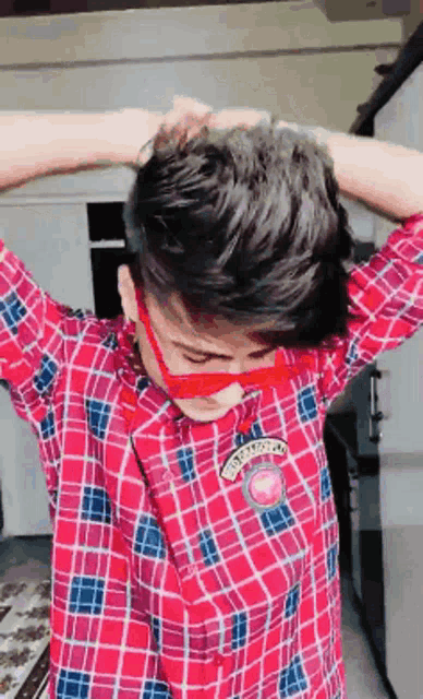 a young man wearing a plaid shirt and red sunglasses with the word tokyo on the sleeve