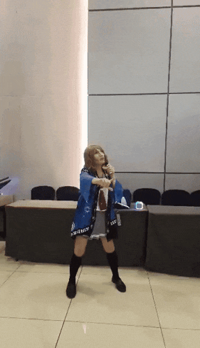 a woman in a blue kimono is dancing with a microphone