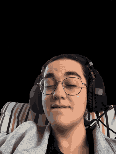 a person wearing glasses and headphones is laying on a striped pillow