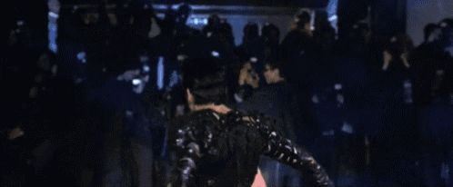 a man is dancing in front of a crowd in a club .