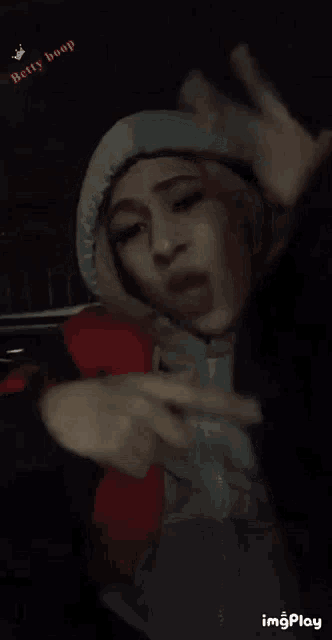 a woman in a hooded jacket making a stop sign with her hands