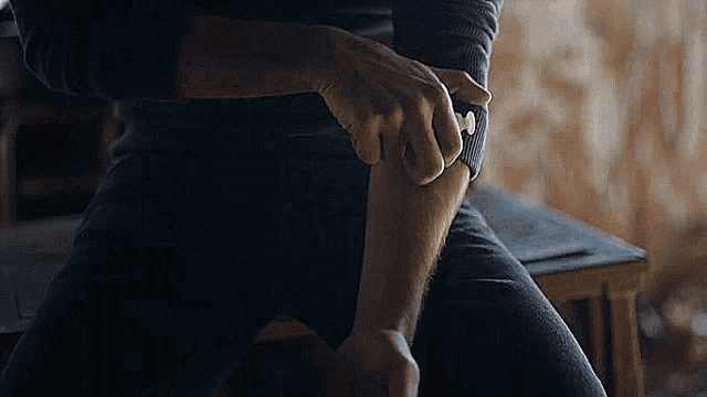 a man is scratching his arm while sitting on a stool .