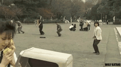 a woman is eating an ice cream cone in a park while a group of people are playing skateboards .