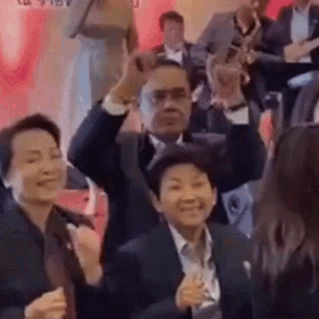 a group of people in suits and ties are dancing in a room .