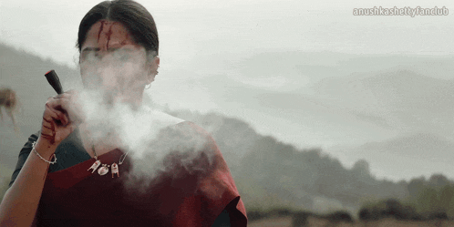 a woman with blood on her face is smoking a cigarette with the words anushkasnetyfanclub written below her