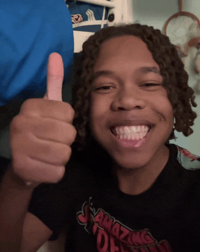 a young man giving a thumbs up and wearing a shirt that says amazing