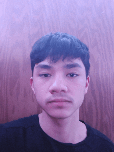 a young man 's face is shown in front of a wooden background