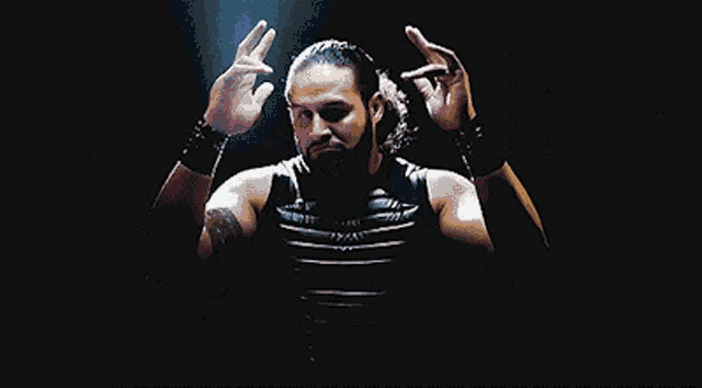 a man with a beard is standing in the dark with his arms outstretched