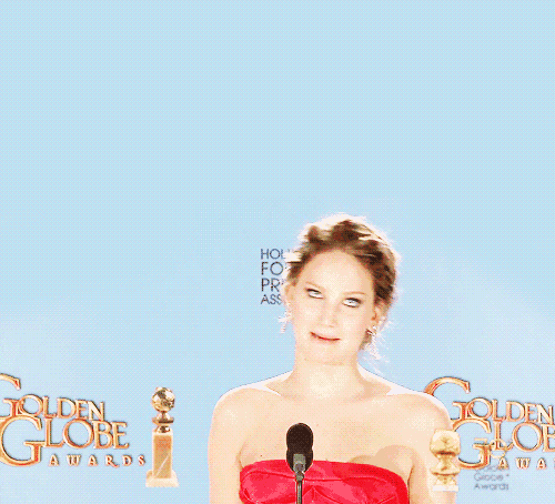 a woman in a red dress stands in front of a microphone at the golden globes awards
