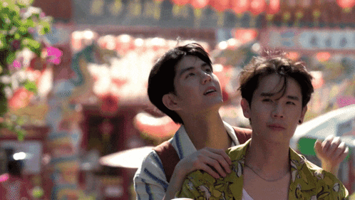 two young men are standing next to each other and one is putting his arm around the other 's neck .