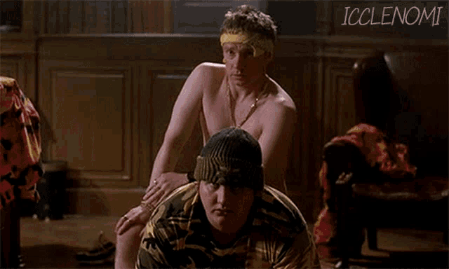 a shirtless man is getting a massage from another shirtless man while wearing a beanie .