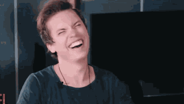 a young man is laughing with his eyes closed