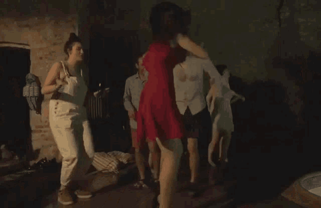 a group of people are dancing in a room with a green wall .