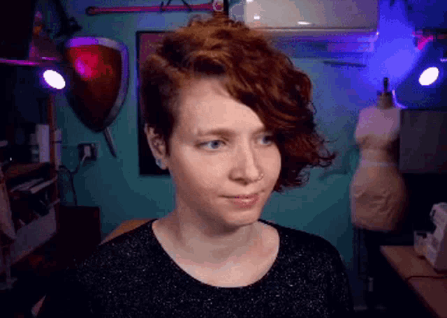 a woman with red hair and a nose ring is looking at the camera