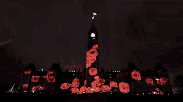a clock tower is lit up at night with red flowers projected onto it