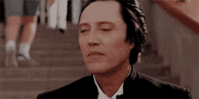 a man in a tuxedo and tie is sitting on a set of stairs .