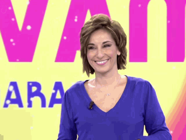 a woman in a blue sweater is smiling in front of a yellow background with the word aran on it