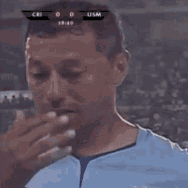 a man is covering his face with his hand while watching a soccer game .