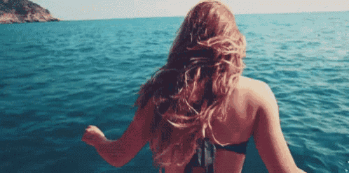 a woman in a bikini is standing in the ocean .