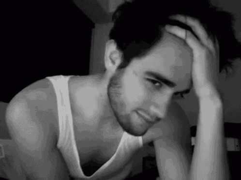 a man in a white tank top has his hand on his forehead
