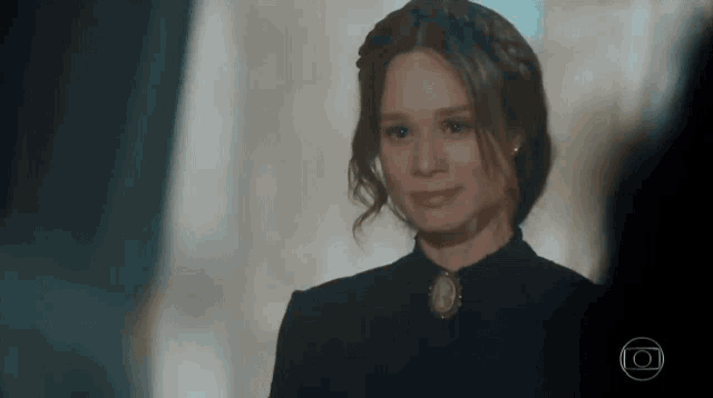 a woman in a black dress is smiling and looking at someone .