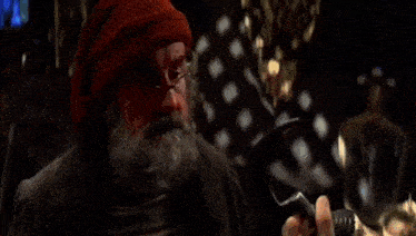 a man with a beard and red hair is talking to another man with long hair .